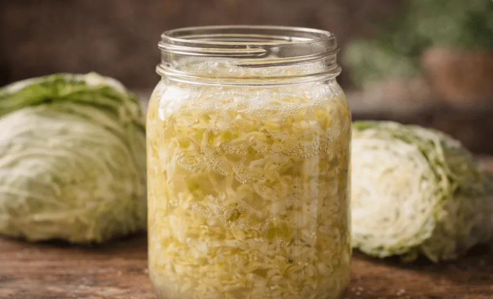 Close-up of bubbling sauerkraut in a glass jar with natural brine, visually defining what is fermented food and its tangy, preserved transformation.