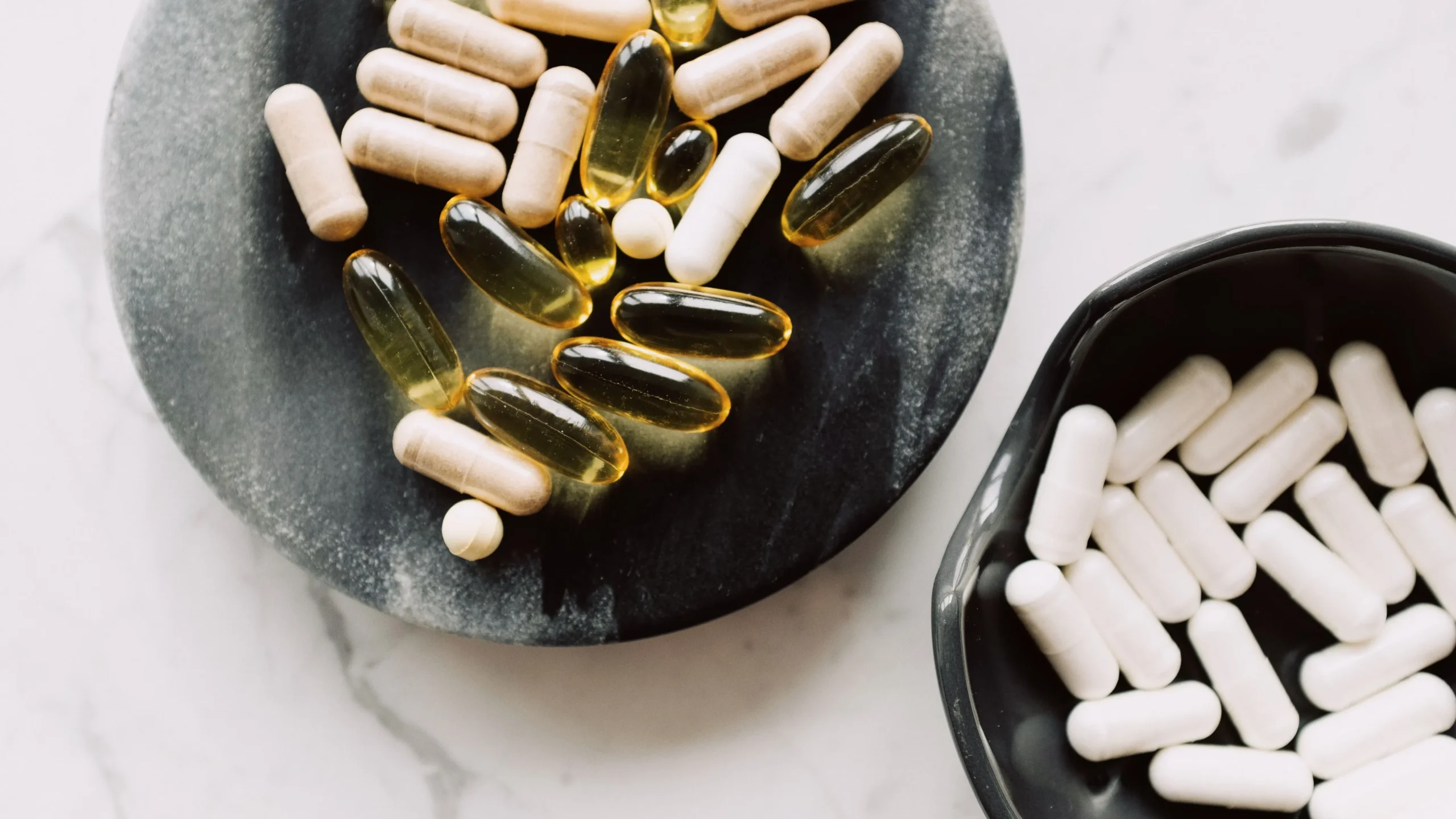 Digestive enzyme capsules placed on a plate with a fork and a meal, representing how the best gut health supplements aid digestion with meals.
