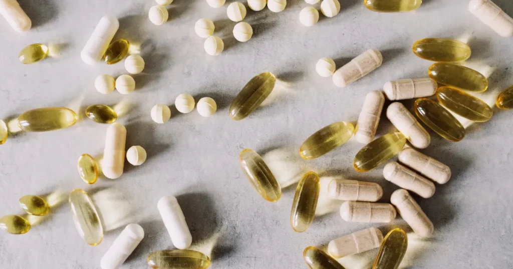 Flat lay of various gut health supplement bottles including probiotics, prebiotics, and digestive enzymes with fresh vegetables, representing the best gut health supplements that actually work in 2026.