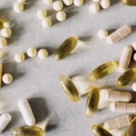 Flat lay of various gut health supplement bottles including probiotics, prebiotics, and digestive enzymes with fresh vegetables, representing the best gut health supplements that actually work in 2026.