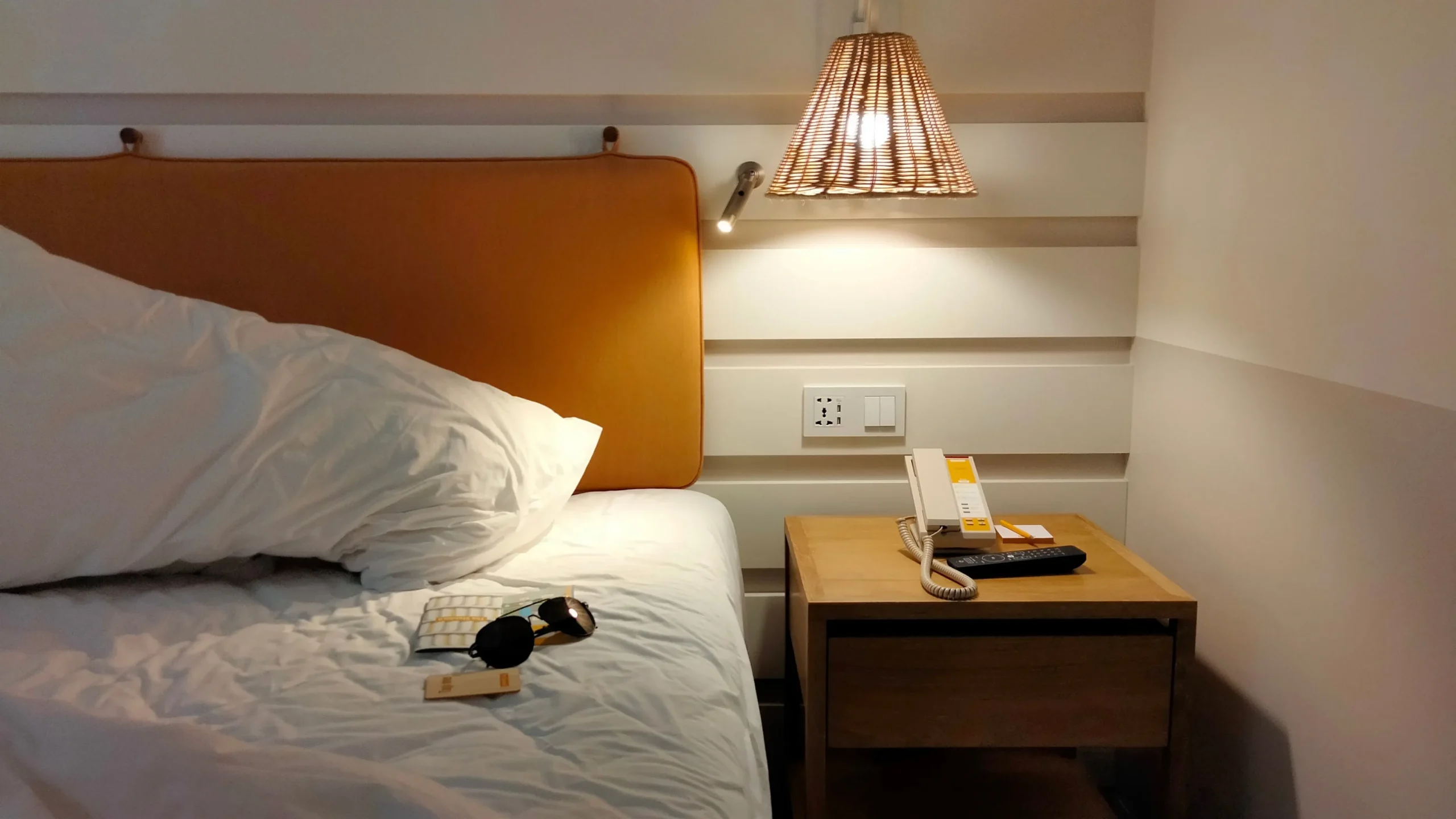 Cozy bedroom with soft lighting, a person stretching or reading, and a phone placed face down away from the bed, supporting the gut-brain axis.