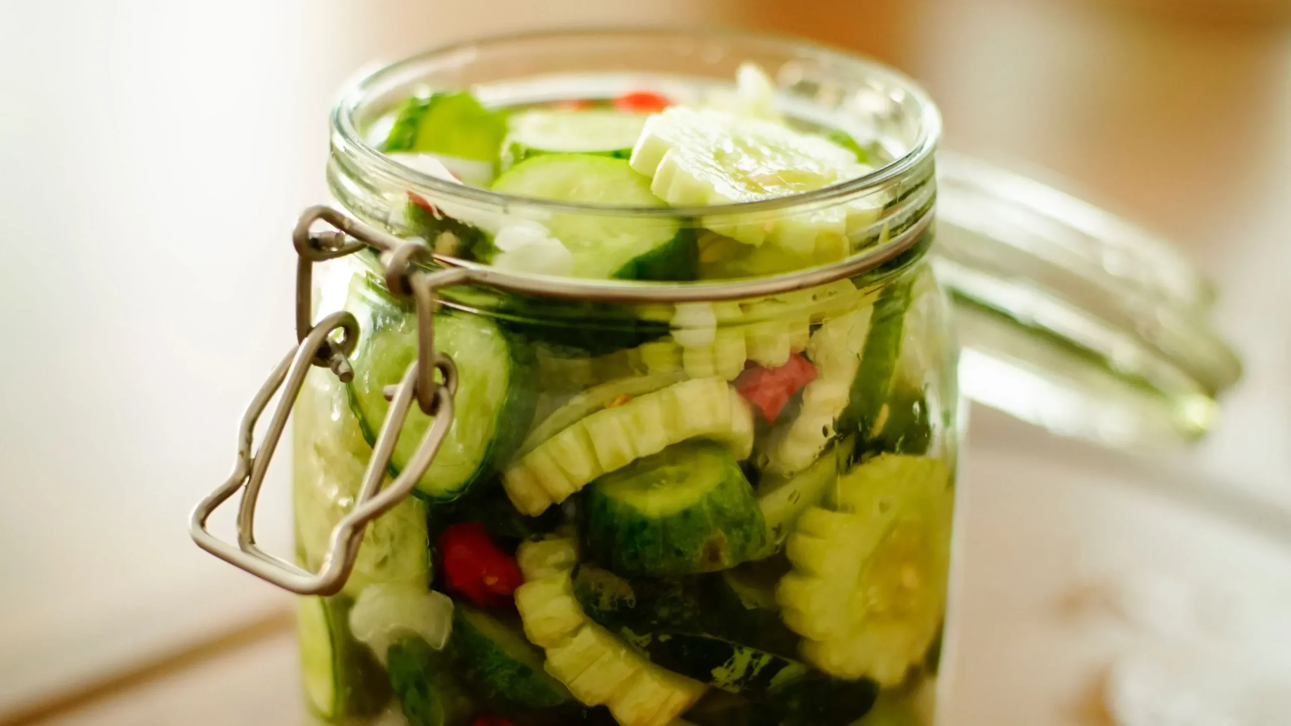 Glass jar of vegetables fermenting under brine with an airlock, illustrating the anaerobic process that explains what is fermented food from start to finish.