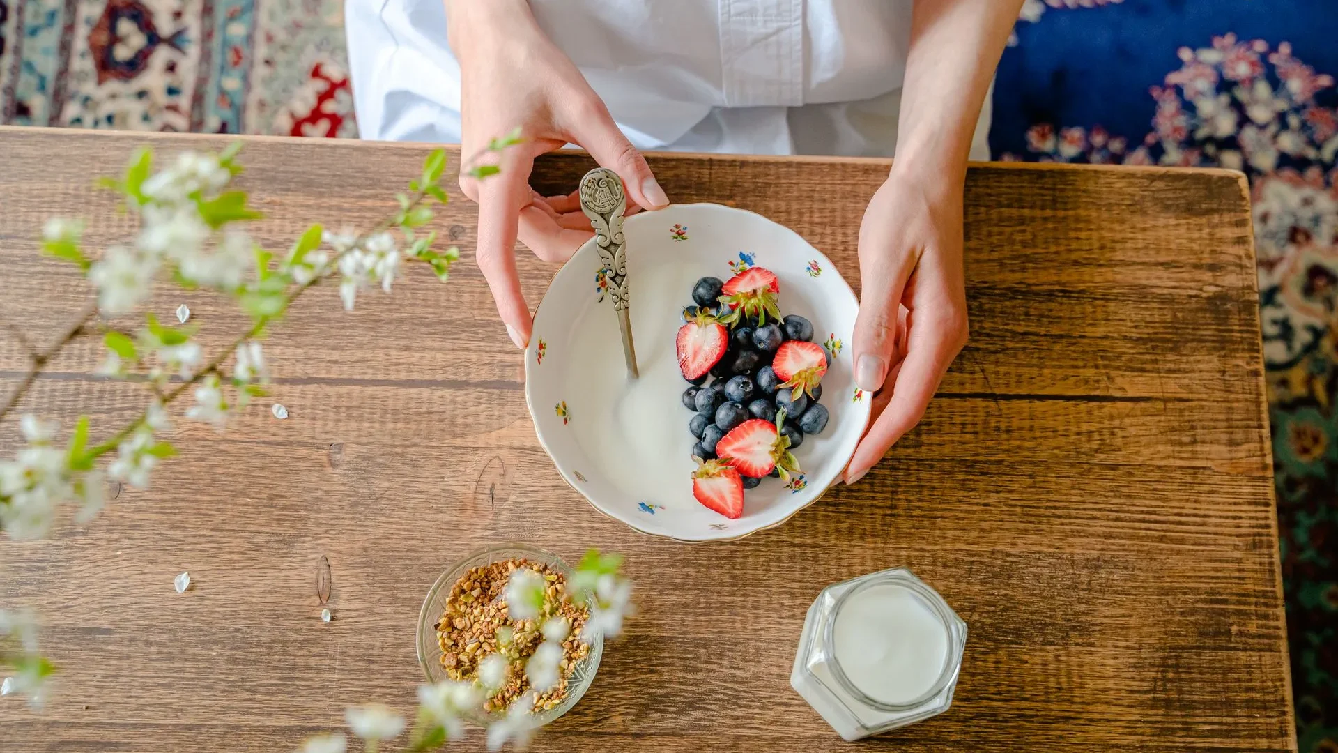  Woman eating a bowl of yogurt topped with fresh berries, highlighting the probiotic, digestive, and nutrient benefits that make what is fermented food so healthy.