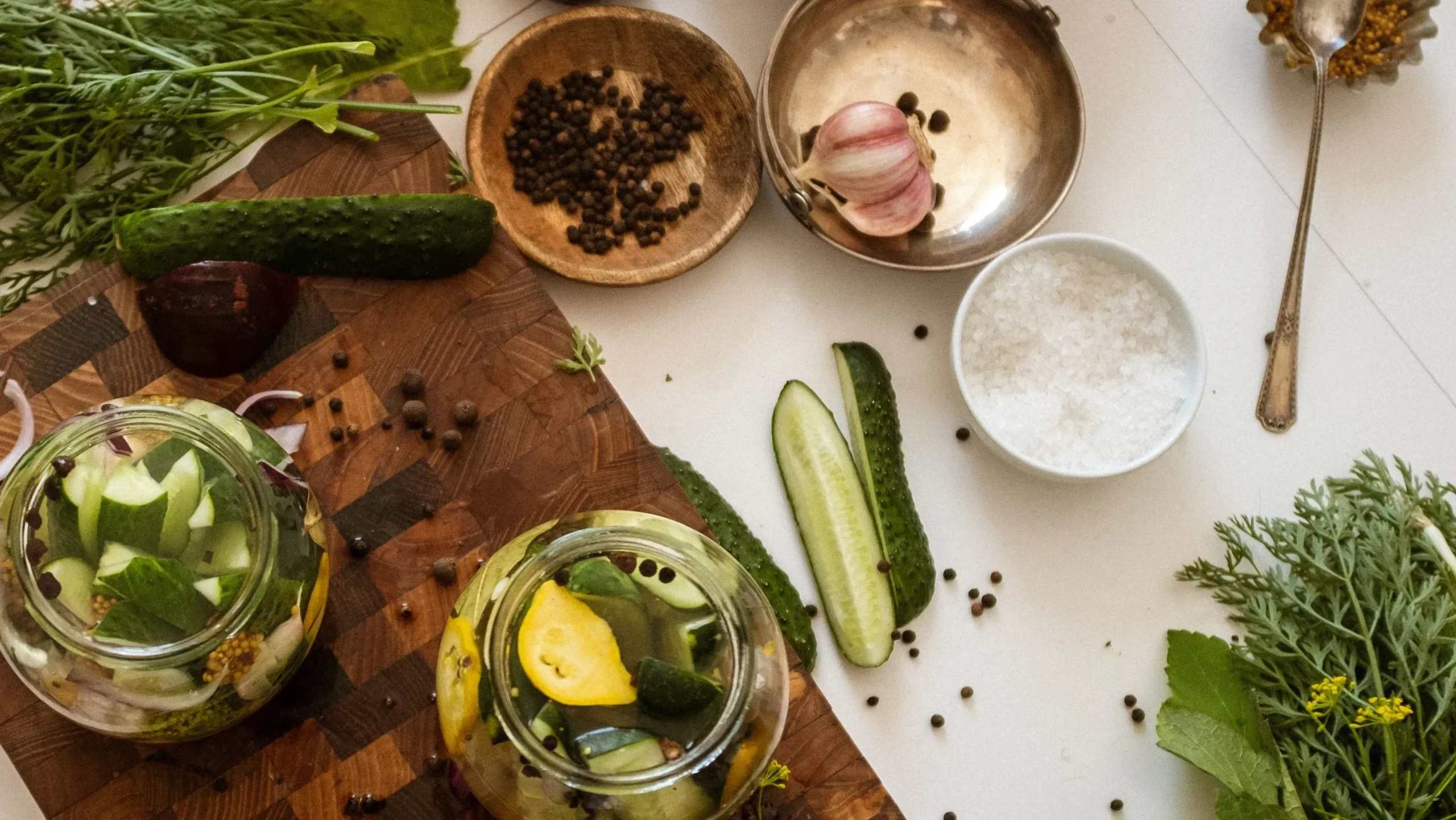 Chopped cabbage, salt, and clean glass jars on a kitchen counter, showing the simple supplies needed to create what is fermented food at home.