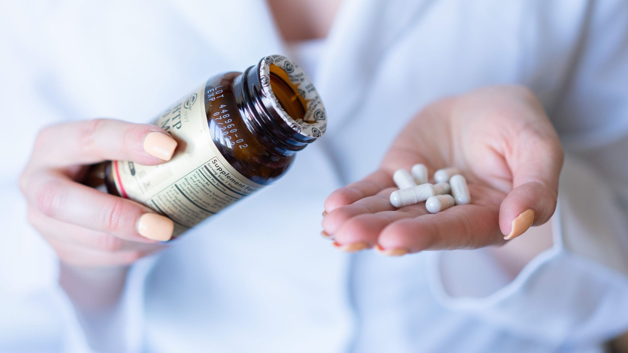 Close-up of hands comparing two supplement labels with a checklist, illustrating how to select the best gut health supplements using quality markers like third-party testing.