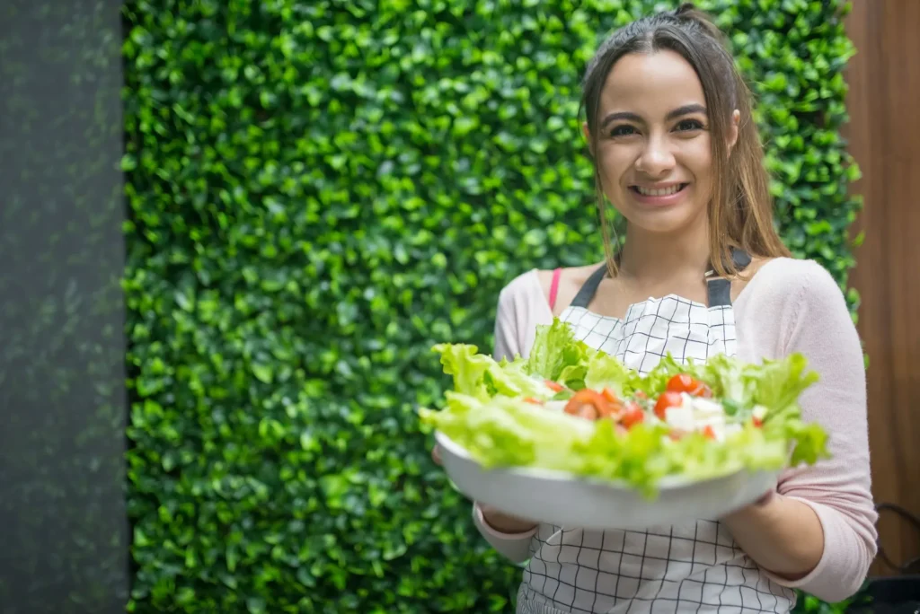 Person smiling and holding a bowl of colorful vegetables and fermented foods, ready to start improving their gut health naturally.