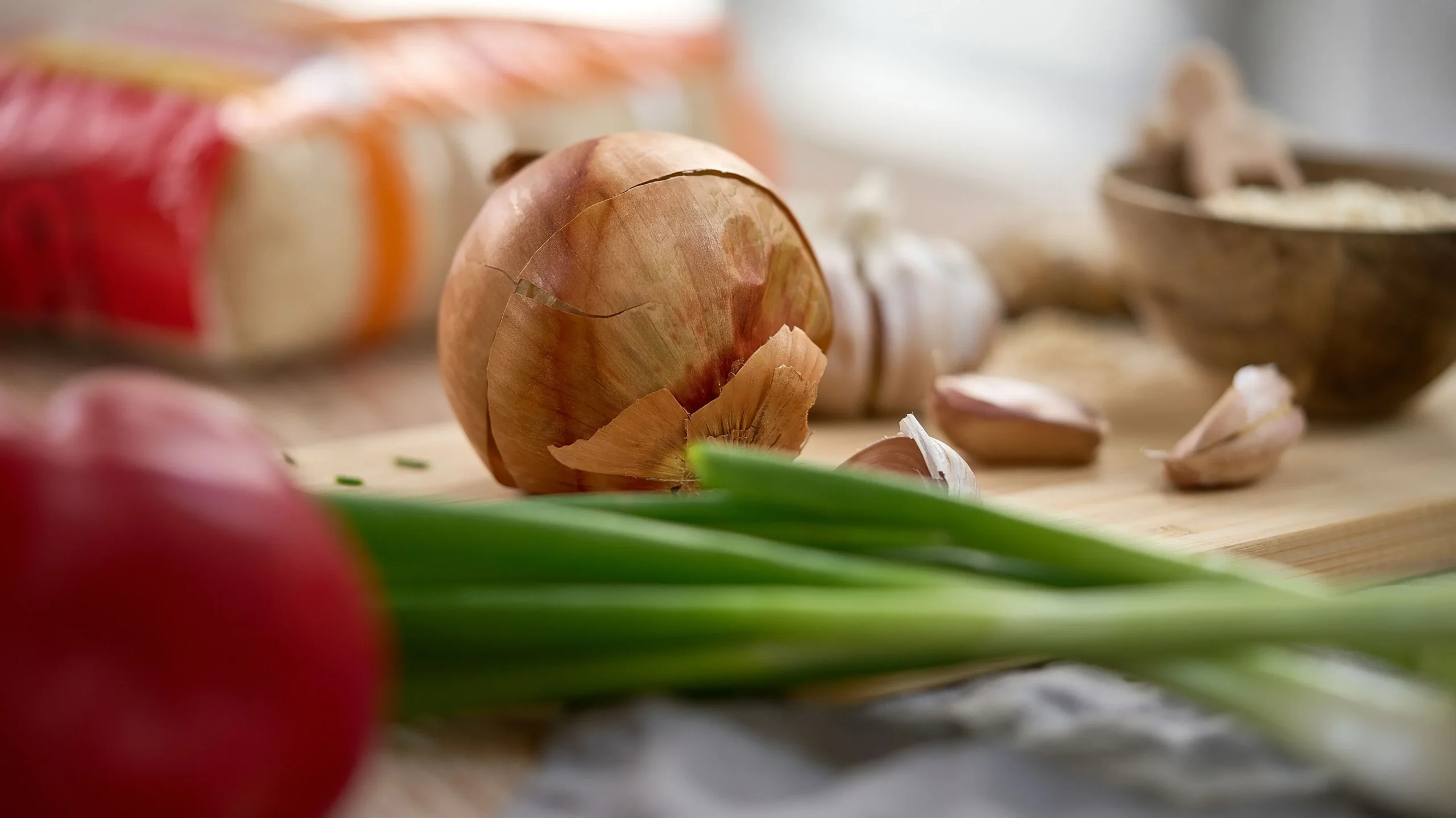  A glass of kefir surrounded by prebiotic foods like garlic, banana, onion, and asparagus, showing how to pair the best probiotic drinks for optimal gut health.