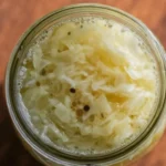 A jar of raw sauerkraut with a spoonful, highlighting the sauerkraut benefits for gut health as an affordable probiotic superfood.