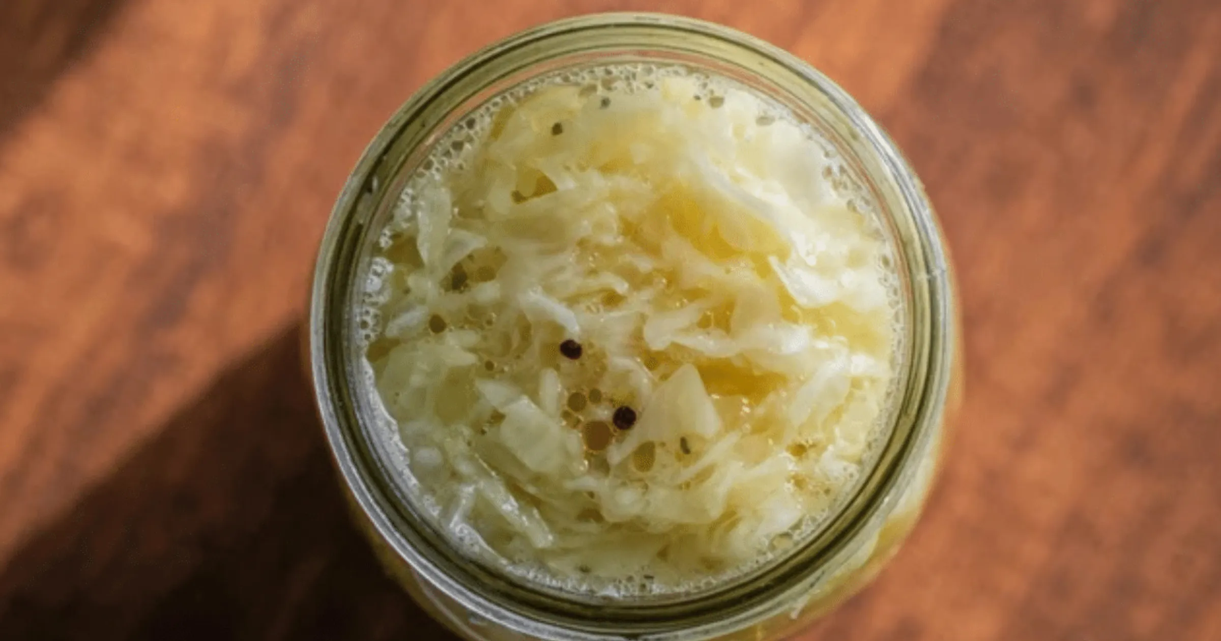 A jar of raw sauerkraut with a spoonful, highlighting the sauerkraut benefits for gut health as an affordable probiotic superfood.