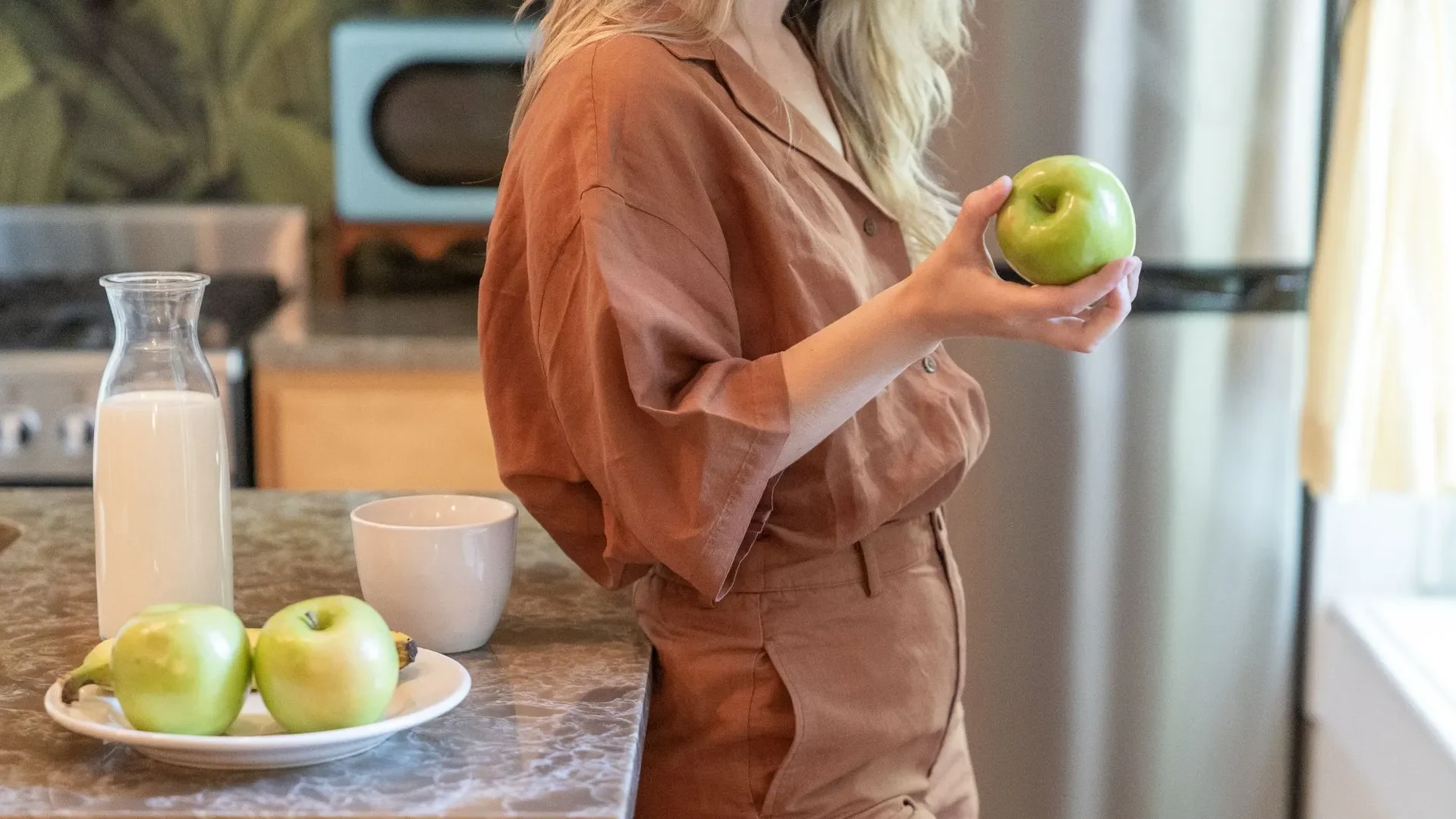 Person smiling while enjoying a bowl of stewed apples in a cozy kitchen, concluding the guide on how stewed apples for gut health offers simple, effective digestive support.