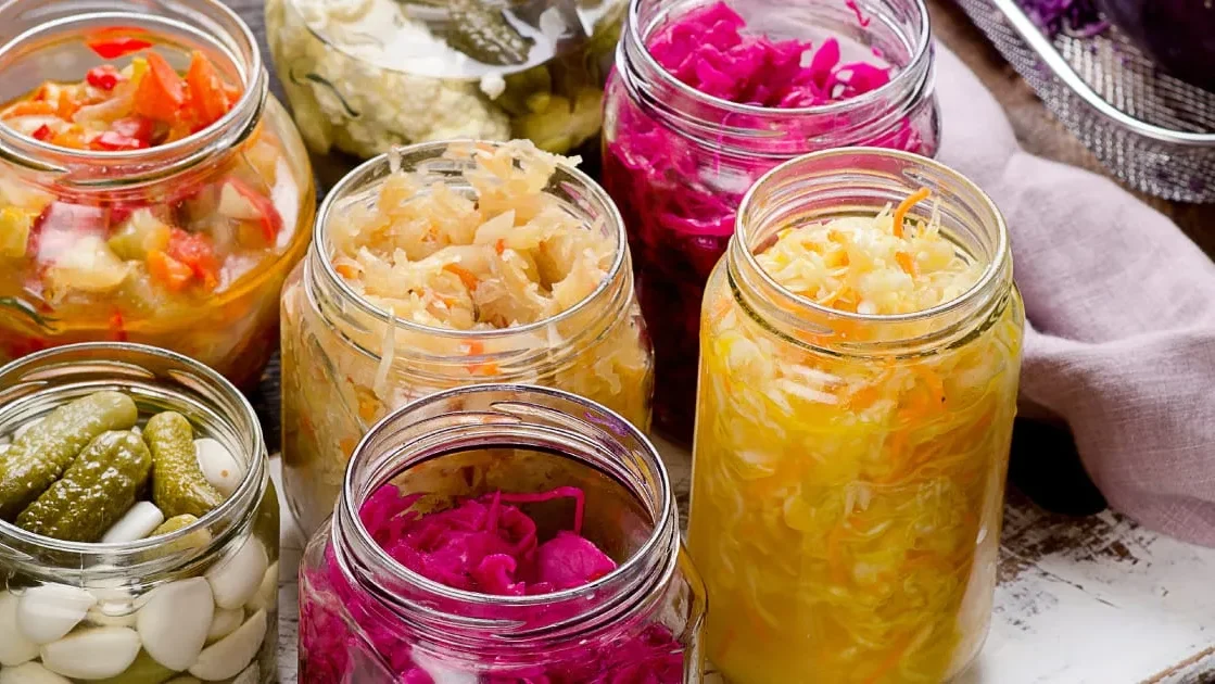 Flat lay of fermented food categories including sauerkraut, kombucha, yogurt, miso, tempeh, and sourdough bread, showing the wide variety of what is fermented food.