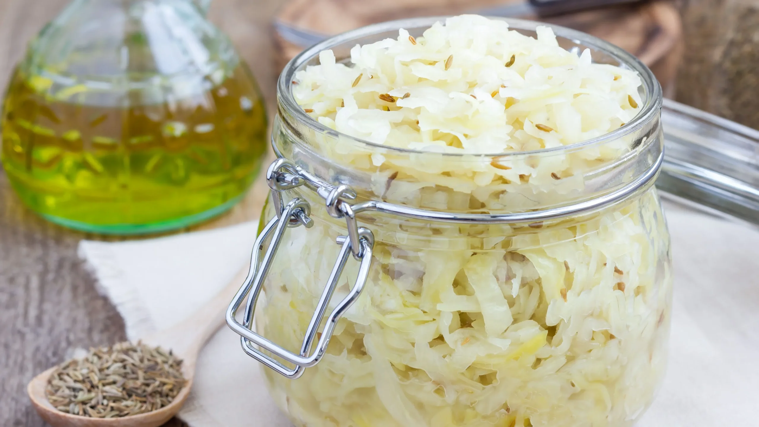 A bowl of sauerkraut surrounded by icons of fiber, enzymes, and vitamins, showing that sauerkraut benefits for gut health go beyond just probiotics.