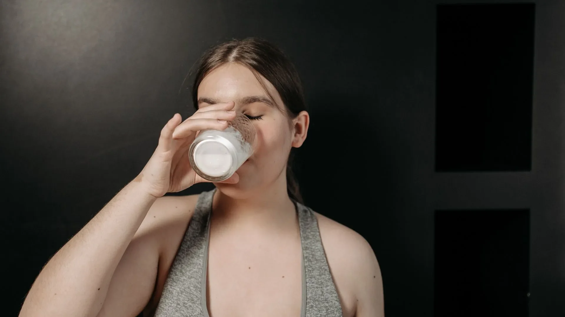 A person smiling and drinking kefir outdoors, concluding the guide to kefir benefits for gut health and its superiority over yogurt for many people.