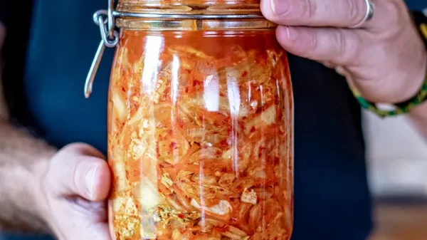 Person smiling proudly with a jar of fermented kimchi, concluding that daily kimchi benefits for gut health can transform digestion, immunity, and overall wellness.