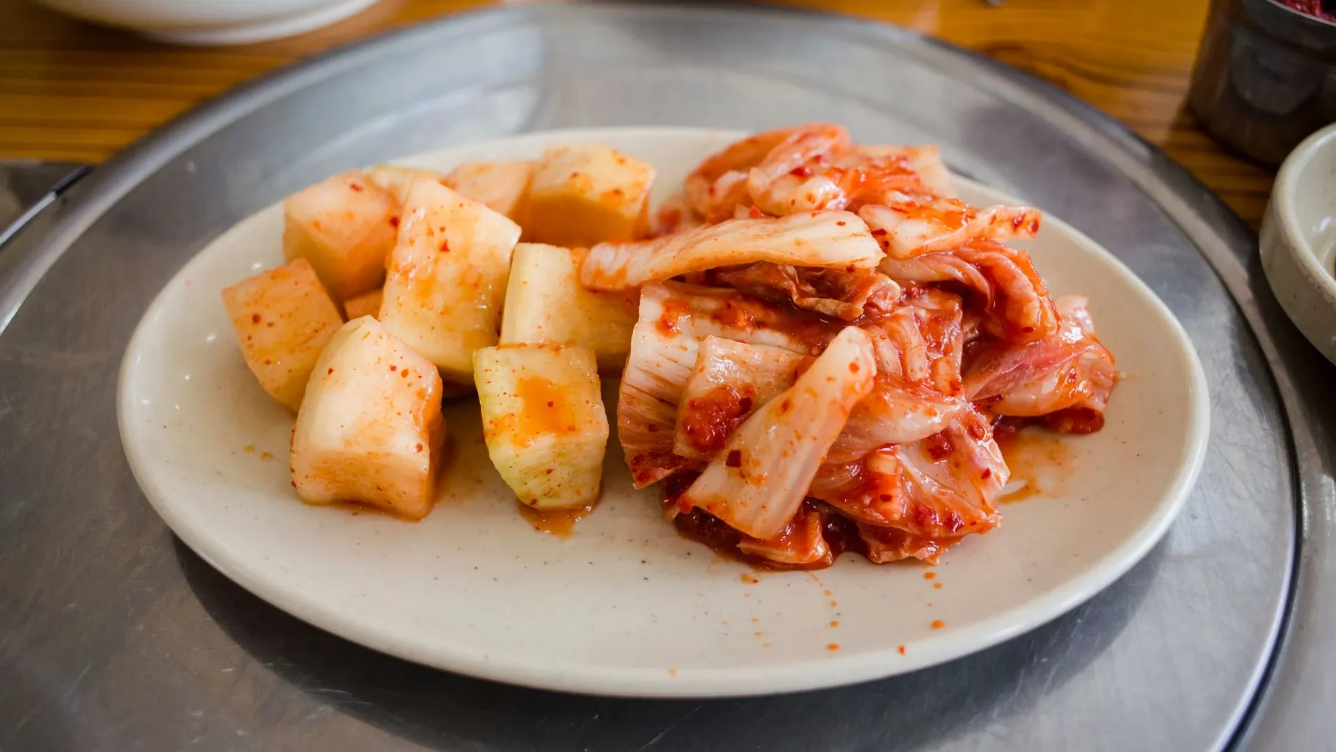 Small spoonful of kimchi next to a low-sodium label and a question mark, guiding how to maximize kimchi benefits for gut health while avoiding initial digestive discomfort.