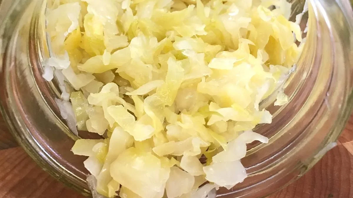 A spoonful of sauerkraut with a microscopic visualization of live probiotic bacteria, illustrating the live cultures that make sauerkraut benefits for gut health so powerful.