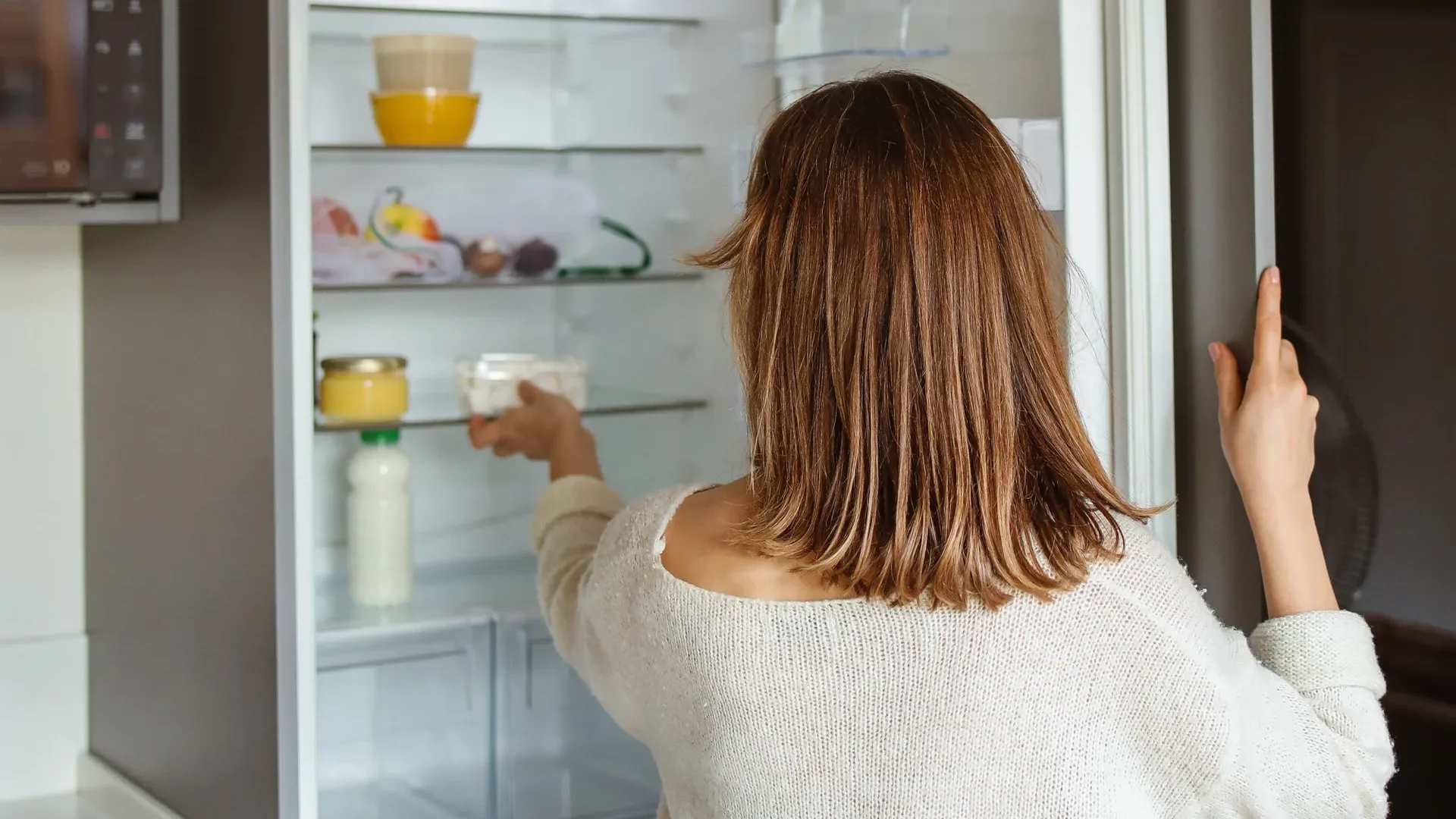 Person smiling and storing yogurt in the fridge, committed to enjoying yogurt benefits for gut health every day for long-term digestive wellness.